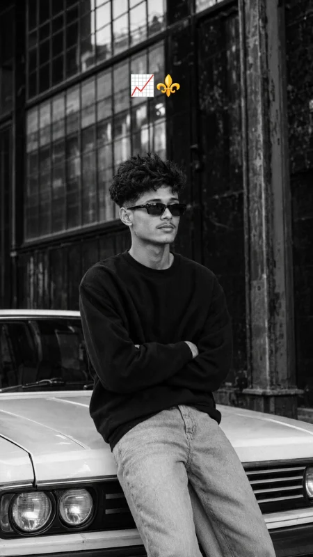 Black and white cinematic urban portrait of a young man sitting on a classic car