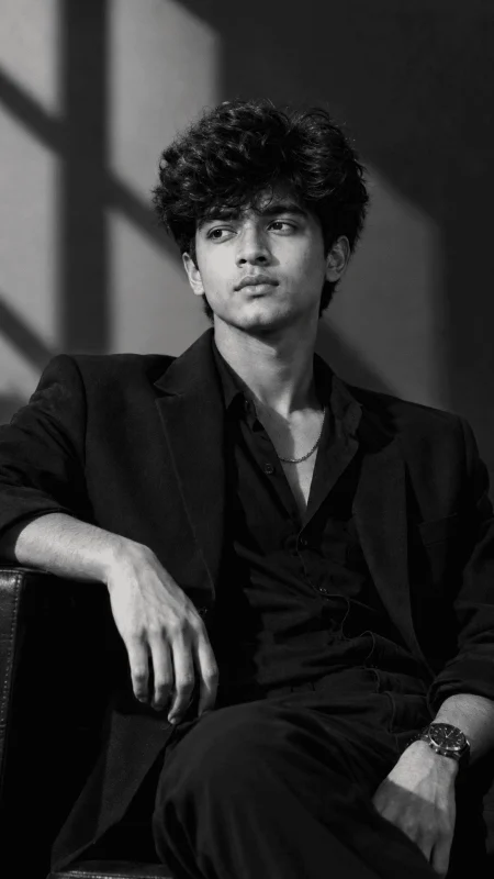 Black and white luxury fashion portrait of a young man sitting in a chair